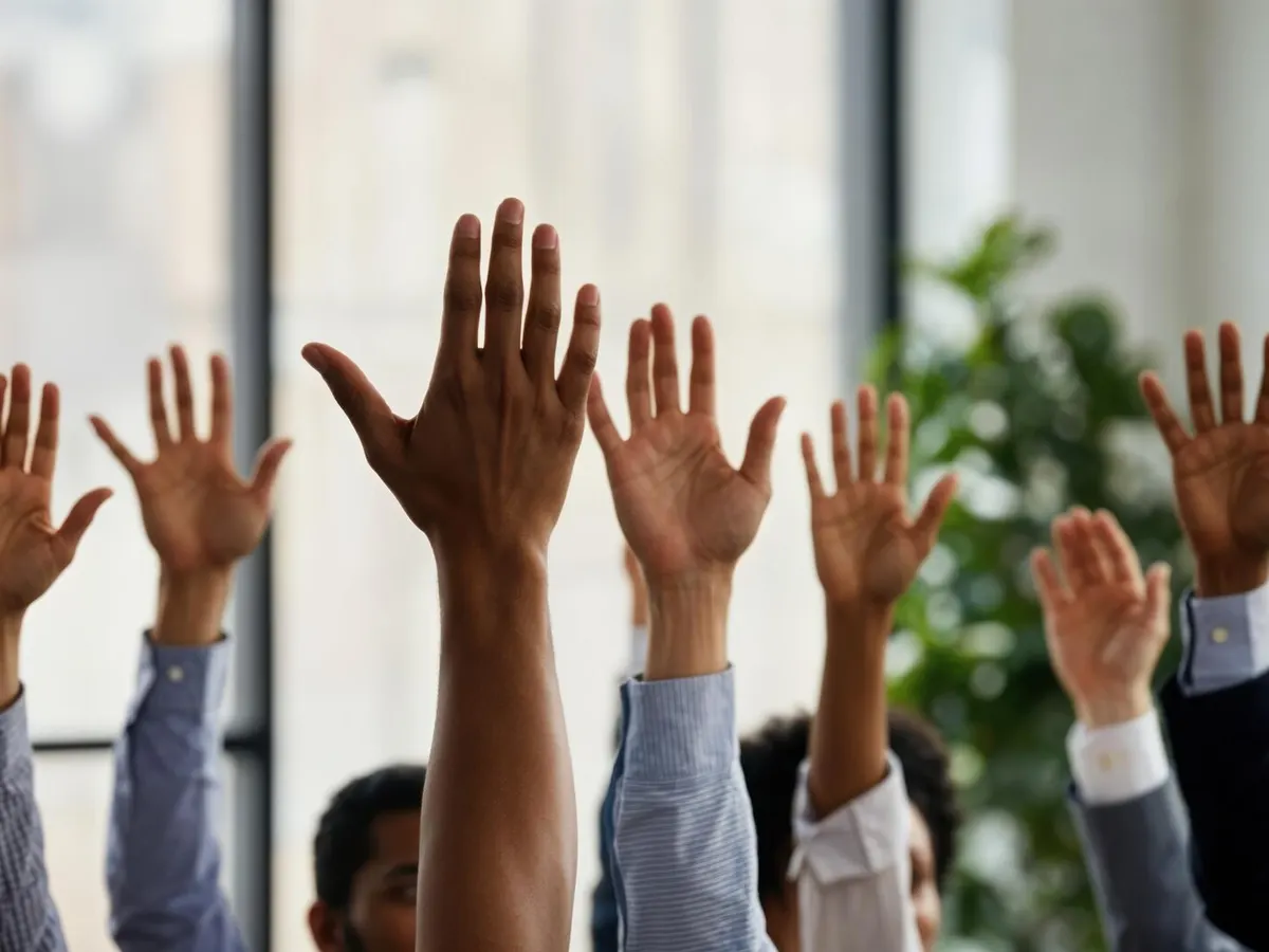 Participants d'une réunion levant la main pour voter une résolution